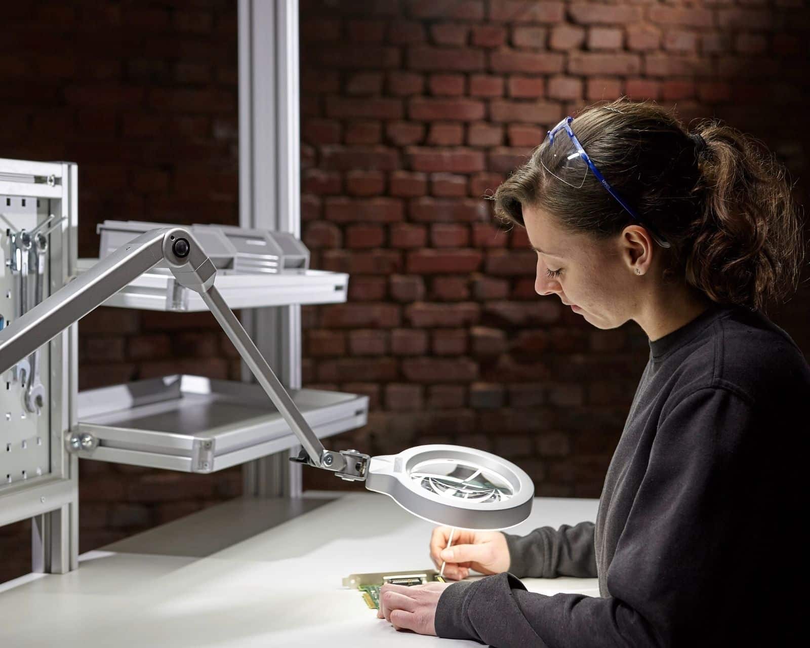 Mitarbeiterin an einem Industrie-Arbeitsplatz mit Systemleuchte