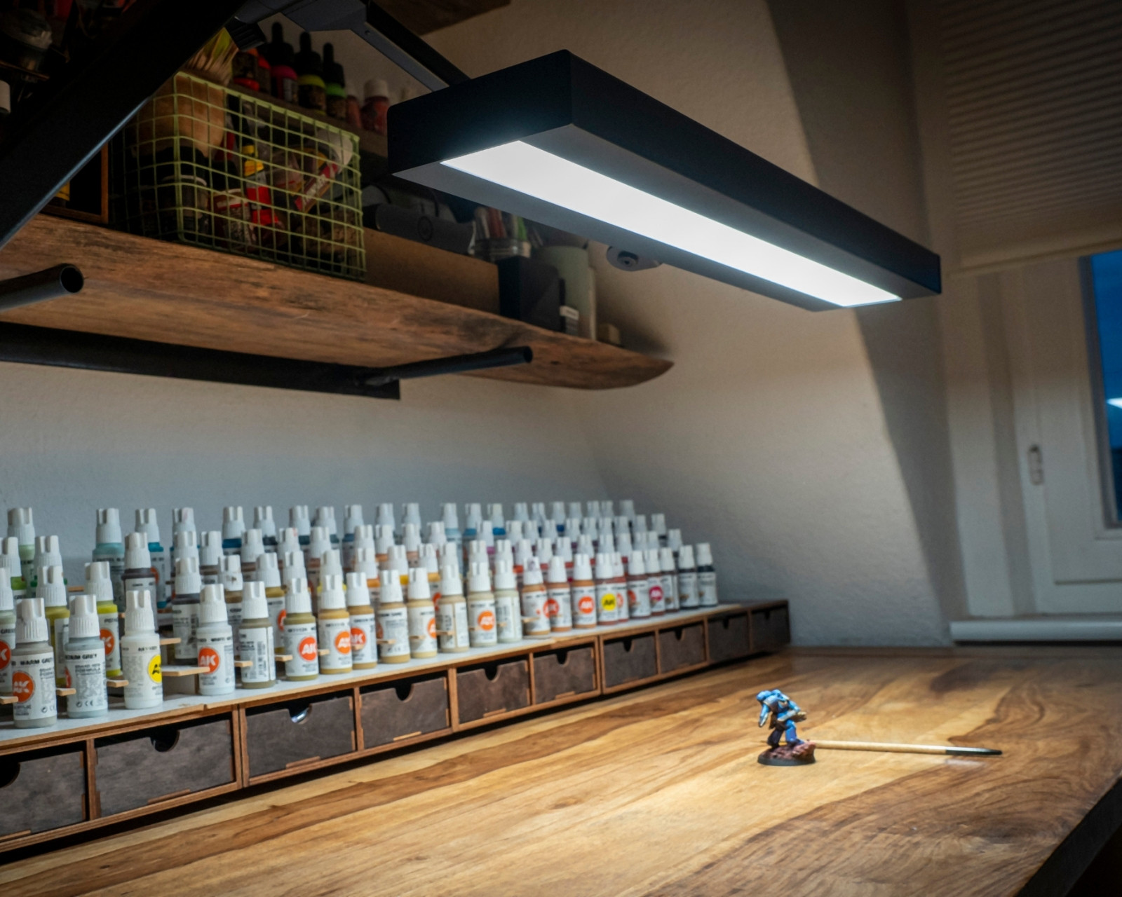 Modellbau-Arbeitsplatz mit Farben und Werkstück unter einer LED-Leuchte